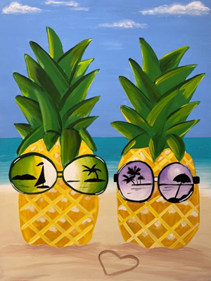 Two yellow pineapples with green leaves stand side by side on a sandy beach, each wearing round sunglasses that reflect tropical scenes like palm trees and an ocean sunset, with a small heart drawn in the sand in front of them.